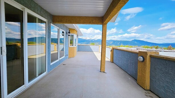 Ein Balkon mit Bergblick, einem Betonboden und Glastüren.