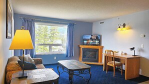 Ein gemütliches Wohnzimmer mit Kamin, Fernseher, Esstisch und einer Couch.