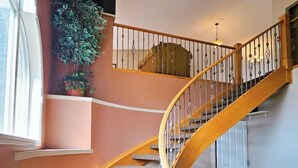 Eine Wendeltreppe mit Holzgeländern und Teppichstufen führt zu einer Zwischenebene mit einem Blumentopf und einer Lampe.