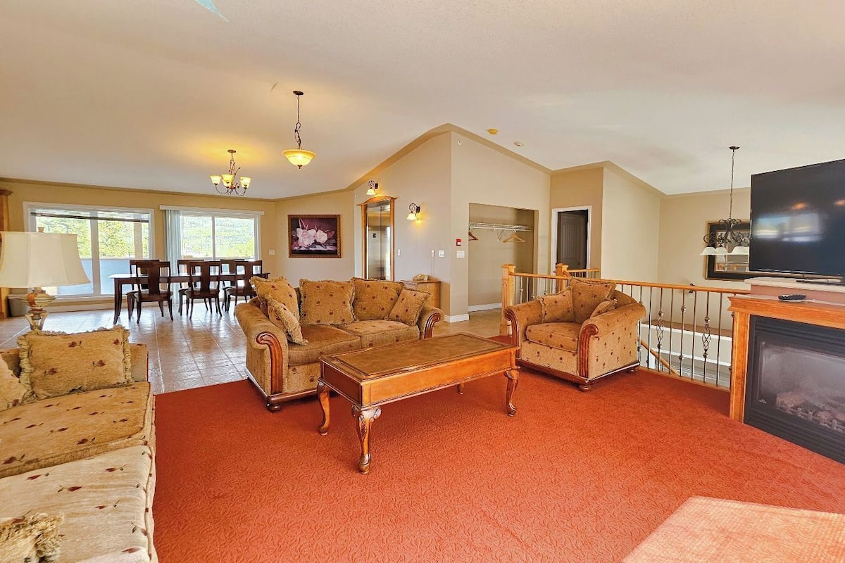 A spacious living room with a fireplace, a television, and a dining area with a table and chairs.