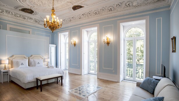 Un dormitorio amplio con una cama grande, un banco, una mesita y un sofá.