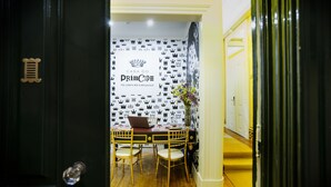 Una habitación con papel tapiz a cuadros en blanco y negro, una computadora portátil sobre una mesa, dos sillas y un florero con flores.