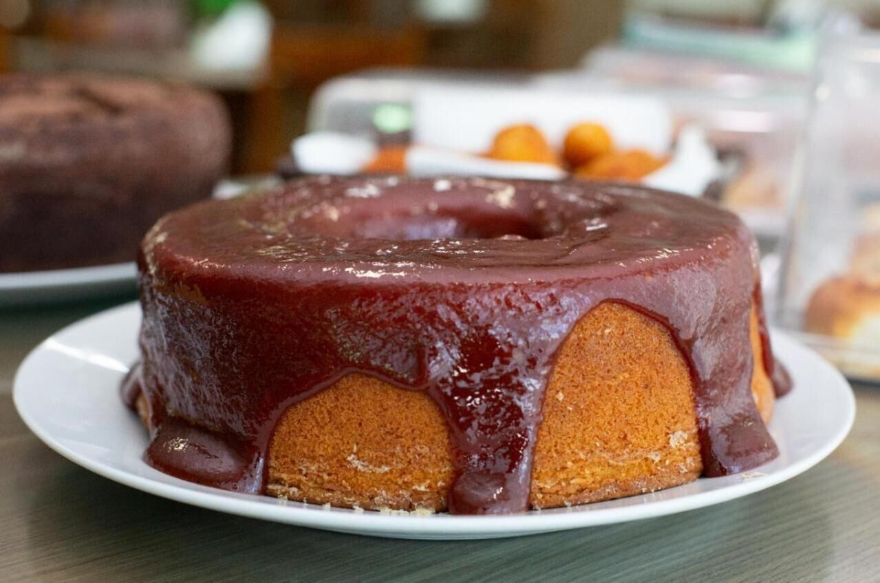 A round cake with a glossy red glaze on a white plate.