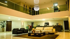 A spacious, modern living area with a high ceiling, a central seating arrangement, and a glass railing overlooking the lower level. - Porto da Serra Hotel (Gravata)
