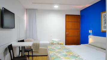 Een hotelkamer met een bed, een bureau met stoel, een televisie en een kledingkast.