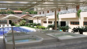 A rooftop pool area with hot tubs and lounge chairs, surrounded by a covered patio and a view of residential buildings. - Porto da Serra Hotel (Gravata)