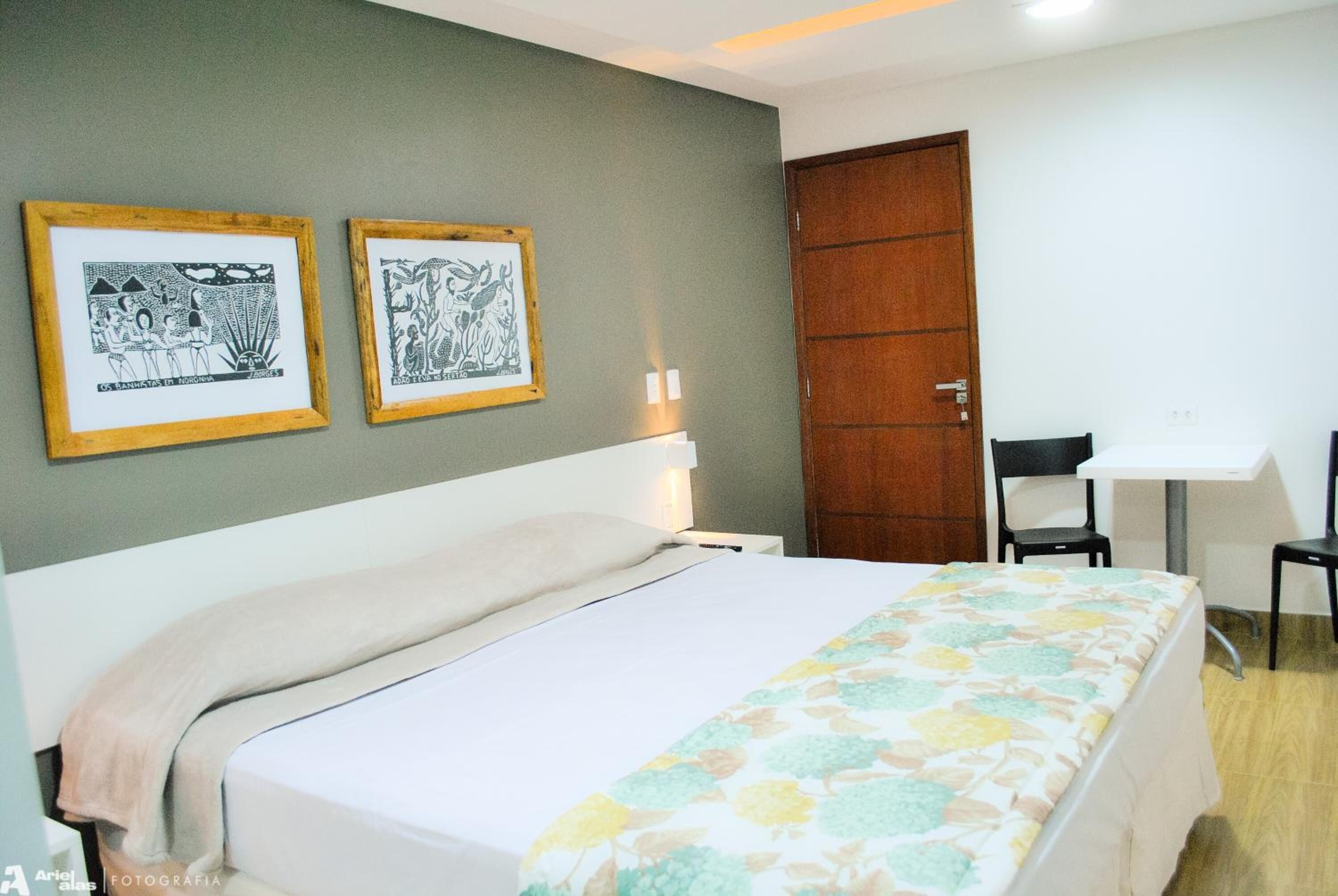 Un dormitorio con una cama, un escritorio y dos cuadros en la pared.