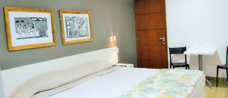 Un dormitorio con una cama, un escritorio y dos cuadros en la pared.