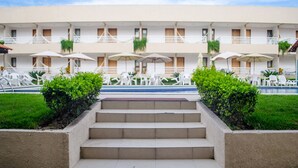 A hotel with a pool, outdoor seating, and a staircase leading to the entrance. - Porto da Serra Hotel (Gravata)