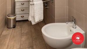 Une salle de bain moderne équipée d’un lavabo, d’un miroir, d’un porte-serviettes et d’une petite poubelle.