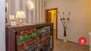 Un comptoir d’accueil orné de valises empilées, d’une lampe, d’un téléphone fixé au mur et d’un vase décoratif.