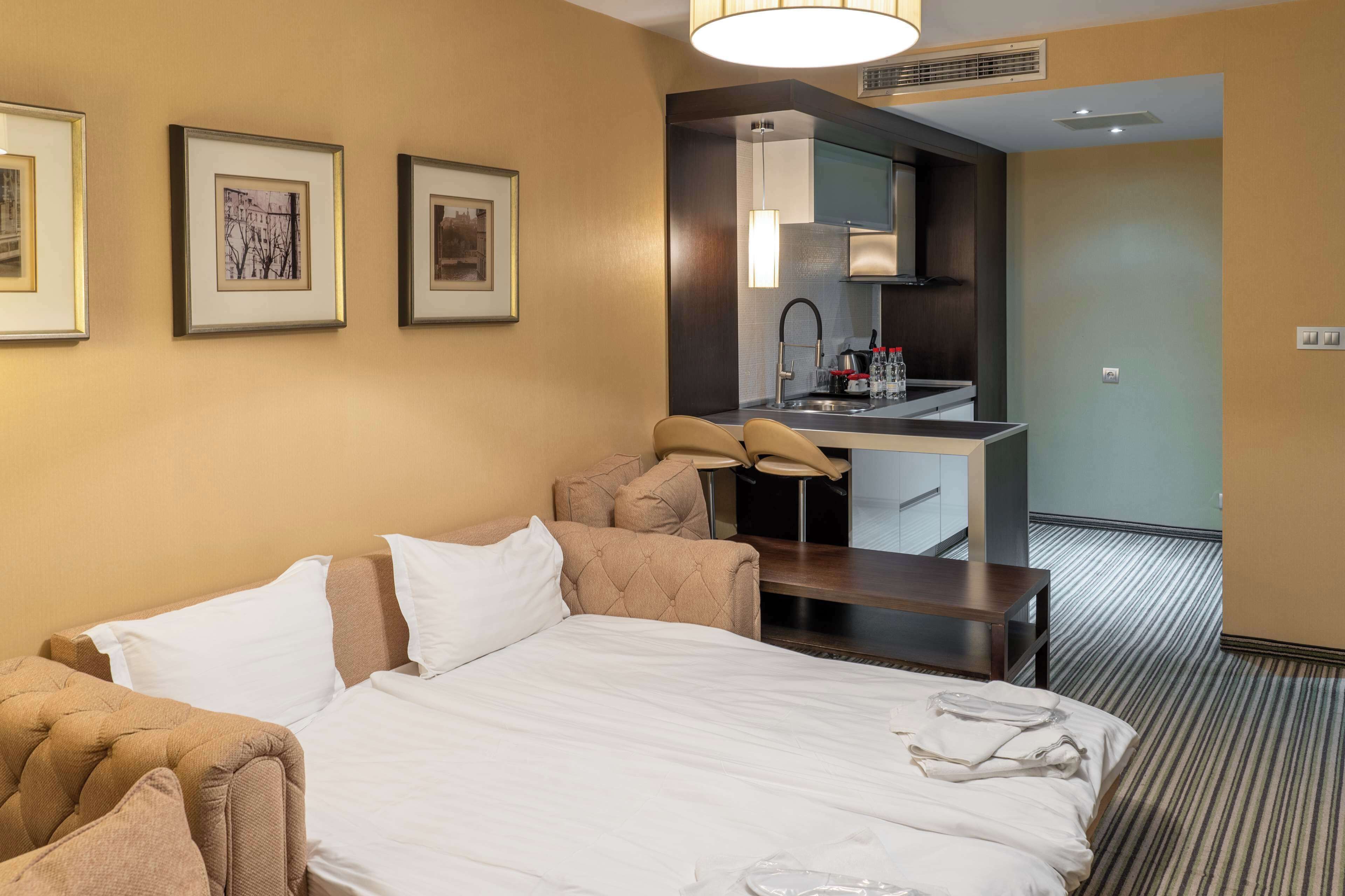 Une chambre d’hôtel comprenant un lit, un canapé, un bureau et une kitchenette.