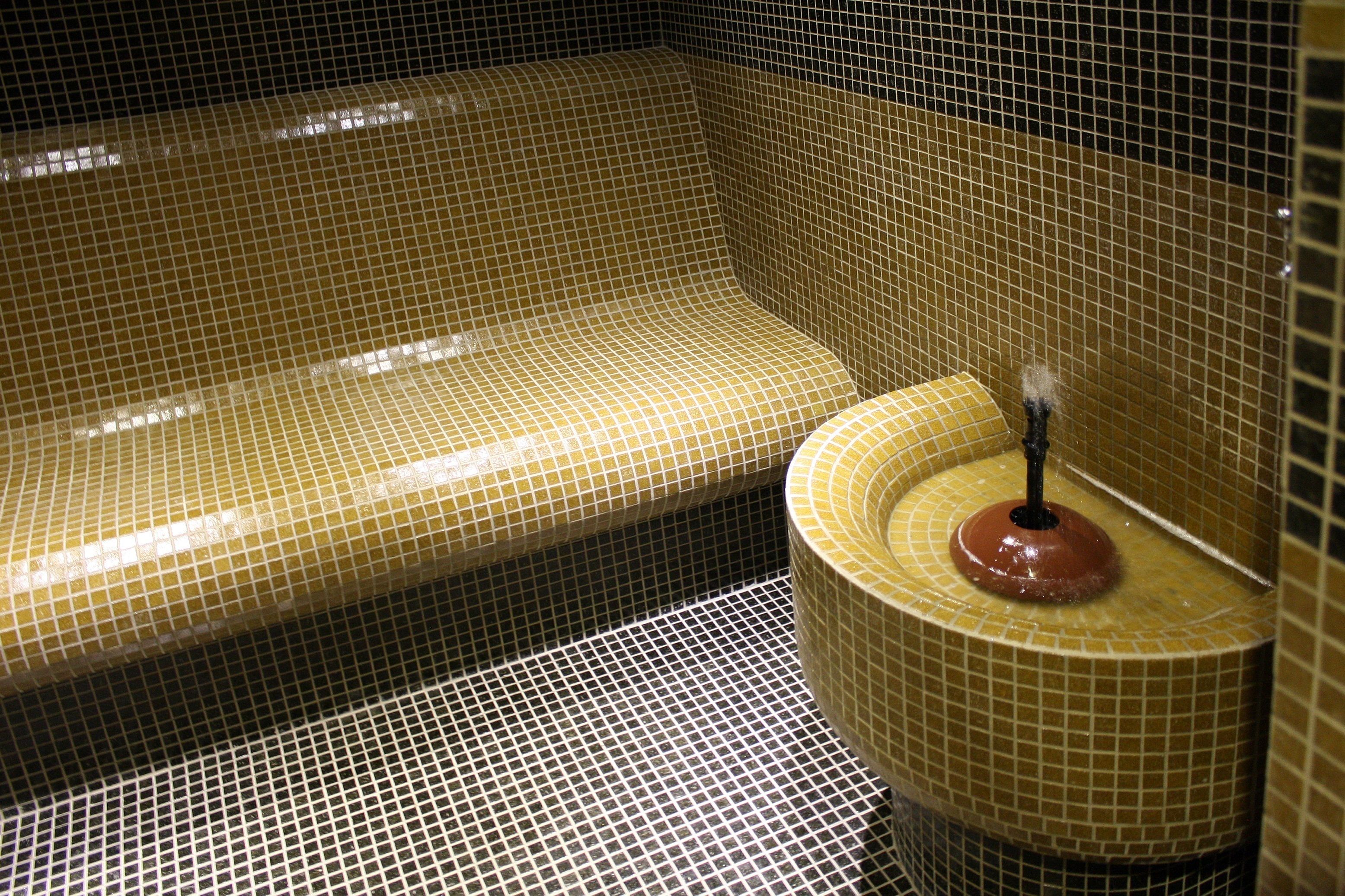 A bathroom with a tiled floor and walls, a bathtub, and a toilet with a round base.