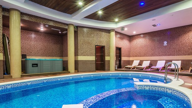 Una piscina con borde de azulejos, un jacuzzi integrado y sillas de descanso.