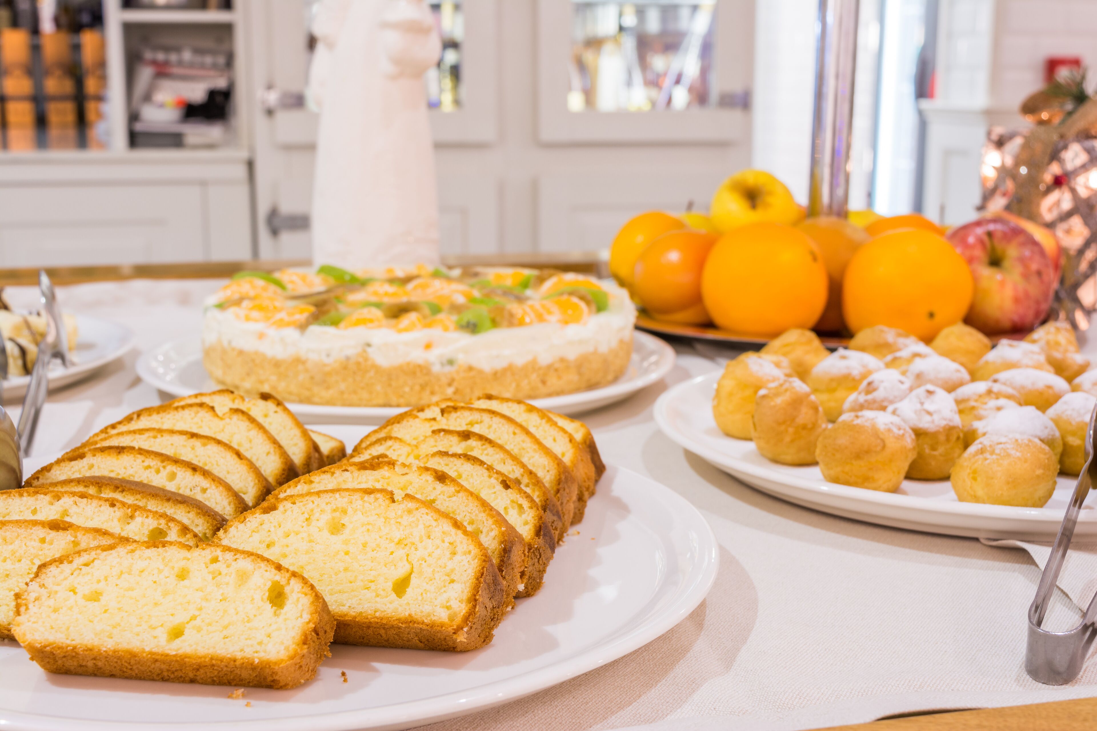 Ein Tisch mit verschiedenen Desserts, darunter ein mehrschichtiger Kuchen, Früchte und Gebäck.