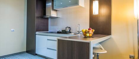 A modern kitchen with a built-in microwave, a kettle, and a fruit bowl on the counter.