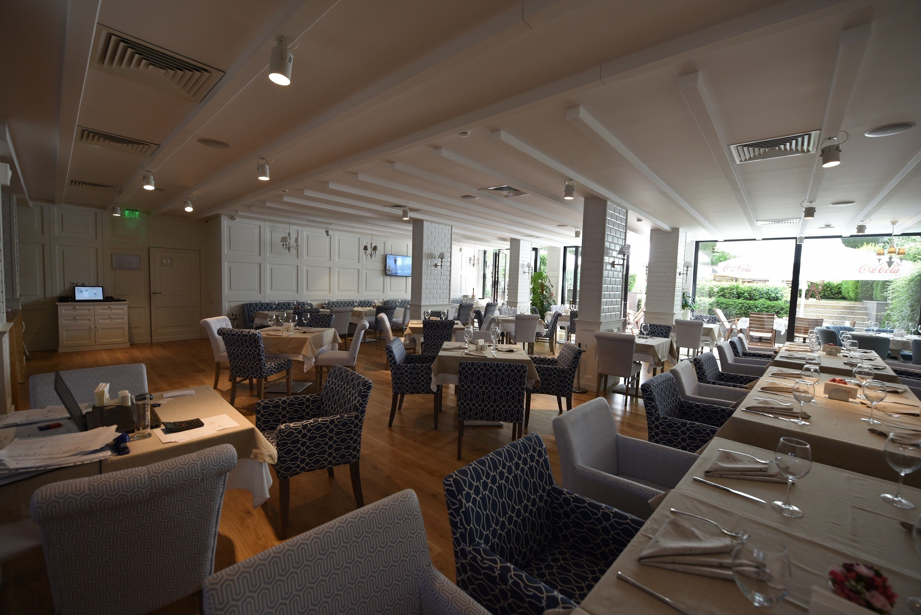 Ein geräumiges Restaurant mit hohen Decken, gemusterten Stühlen und gedeckten Tischen.
