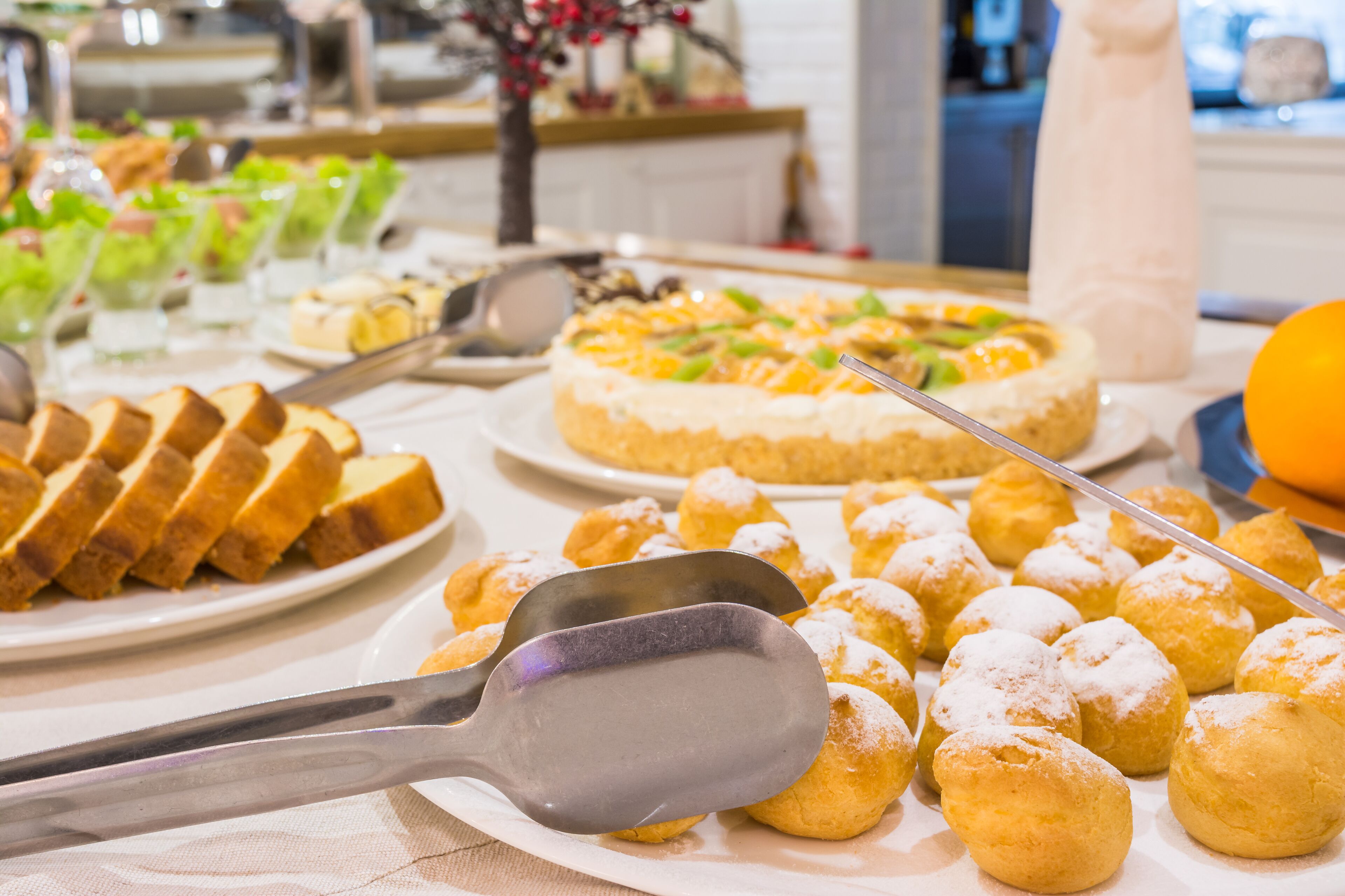 A buffet table with various food items including bread, pastries, and a cake.