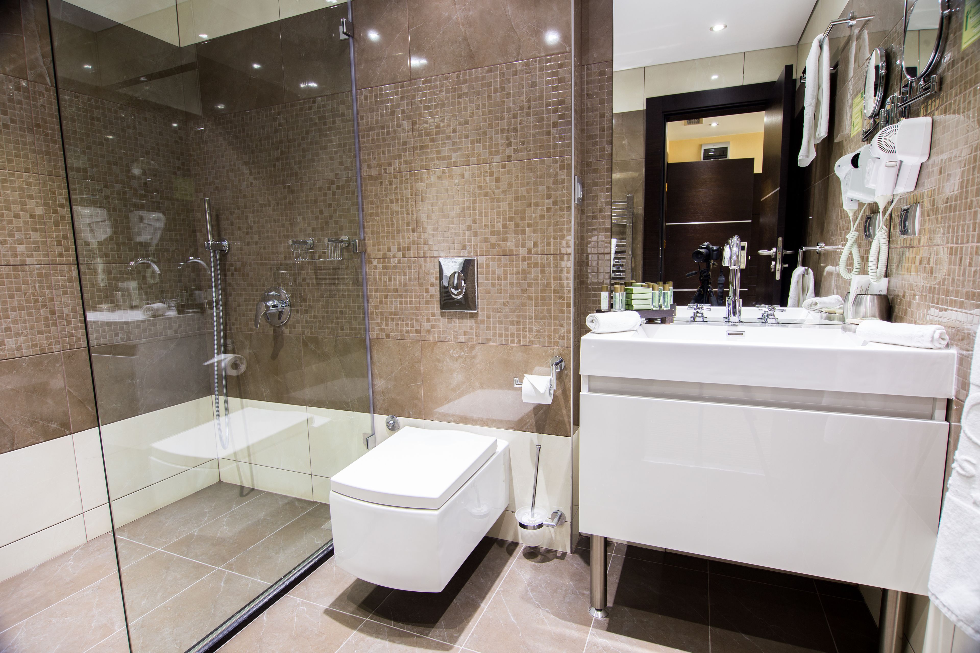 A modern bathroom with a glass-enclosed shower, a white toilet, and a vanity with a mirror.