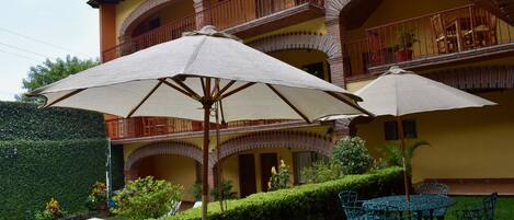 A building with a yellow facade, multiple balconies, and outdoor seating with umbrellas.