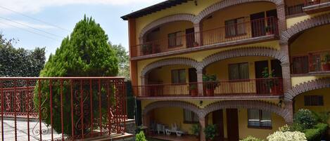 A multi-story building with balconies, a swimming pool, and potted plants.