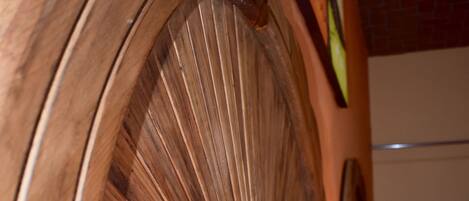 A wooden headboard with a fan-like design, a lamp, and a patterned bedspread.