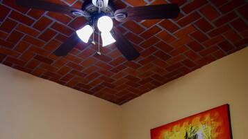 A bedroom with a brick ceiling, a wooden headboard, a green bedspread, and a painting on the wall.