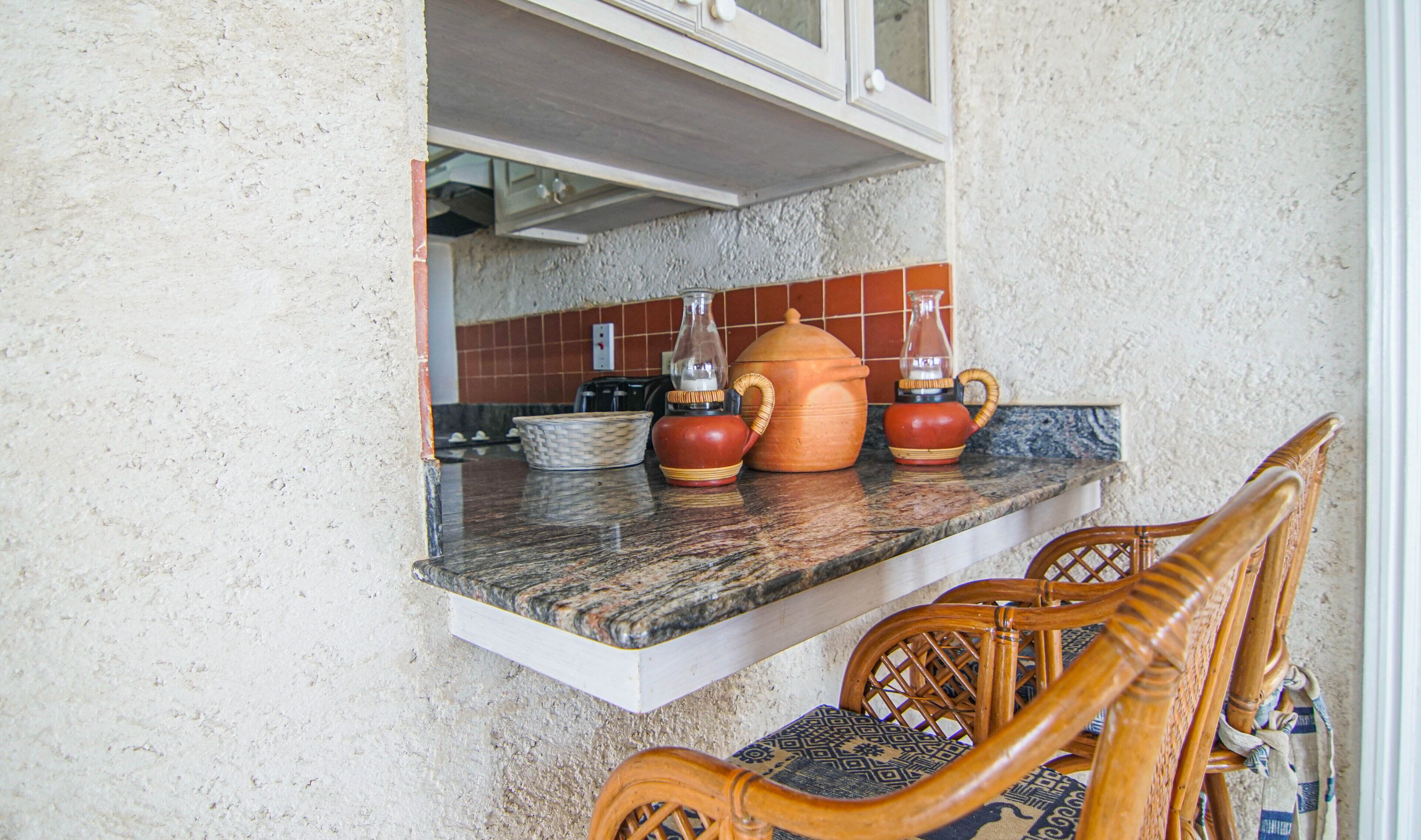A kitchen with a granite countertop, a woven chair, and a window above the sink.
