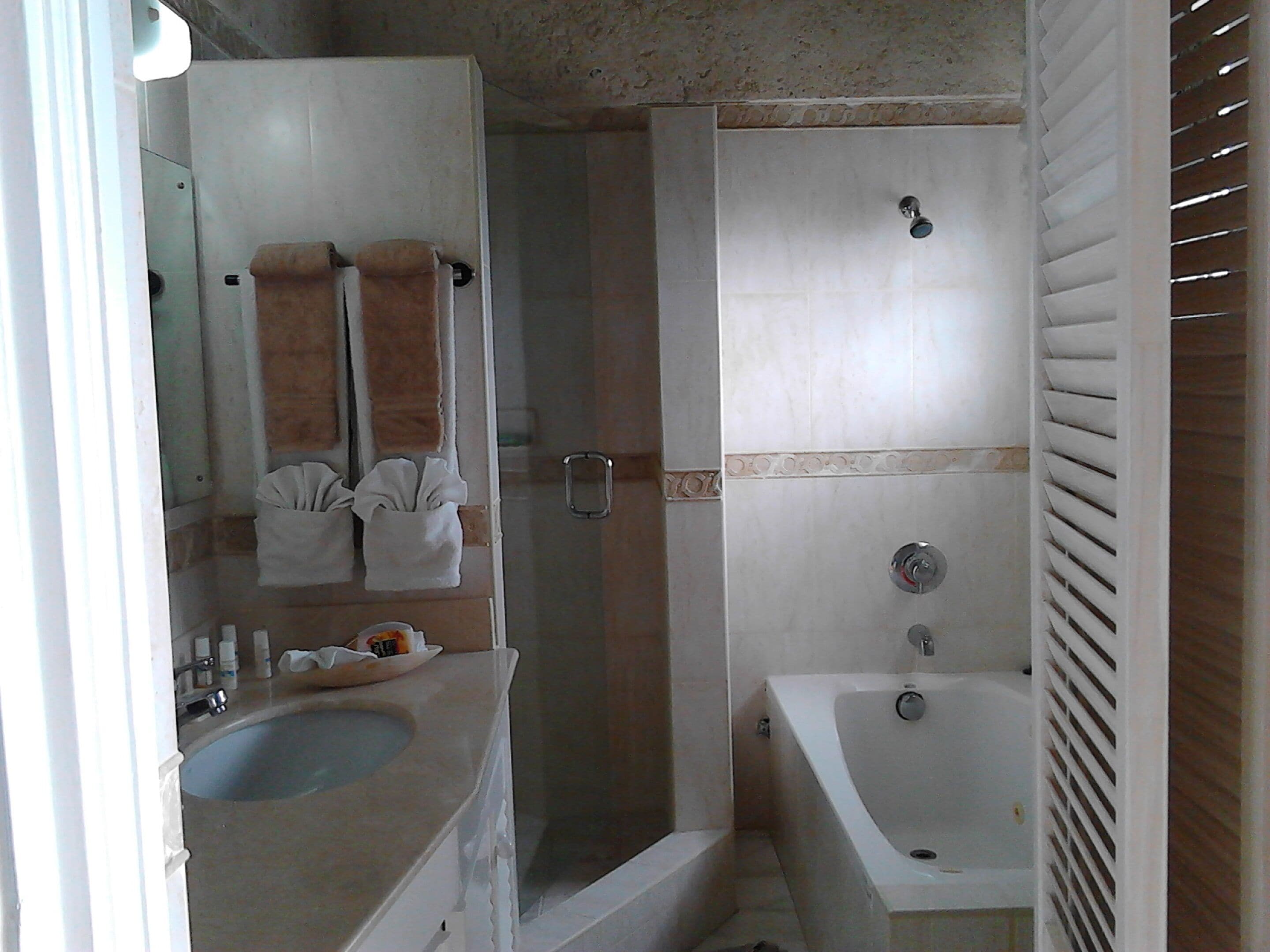 Ein Badezimmer mit Waschbecken, Spiegel, Handtuchhalter, Dusche und Badewanne.