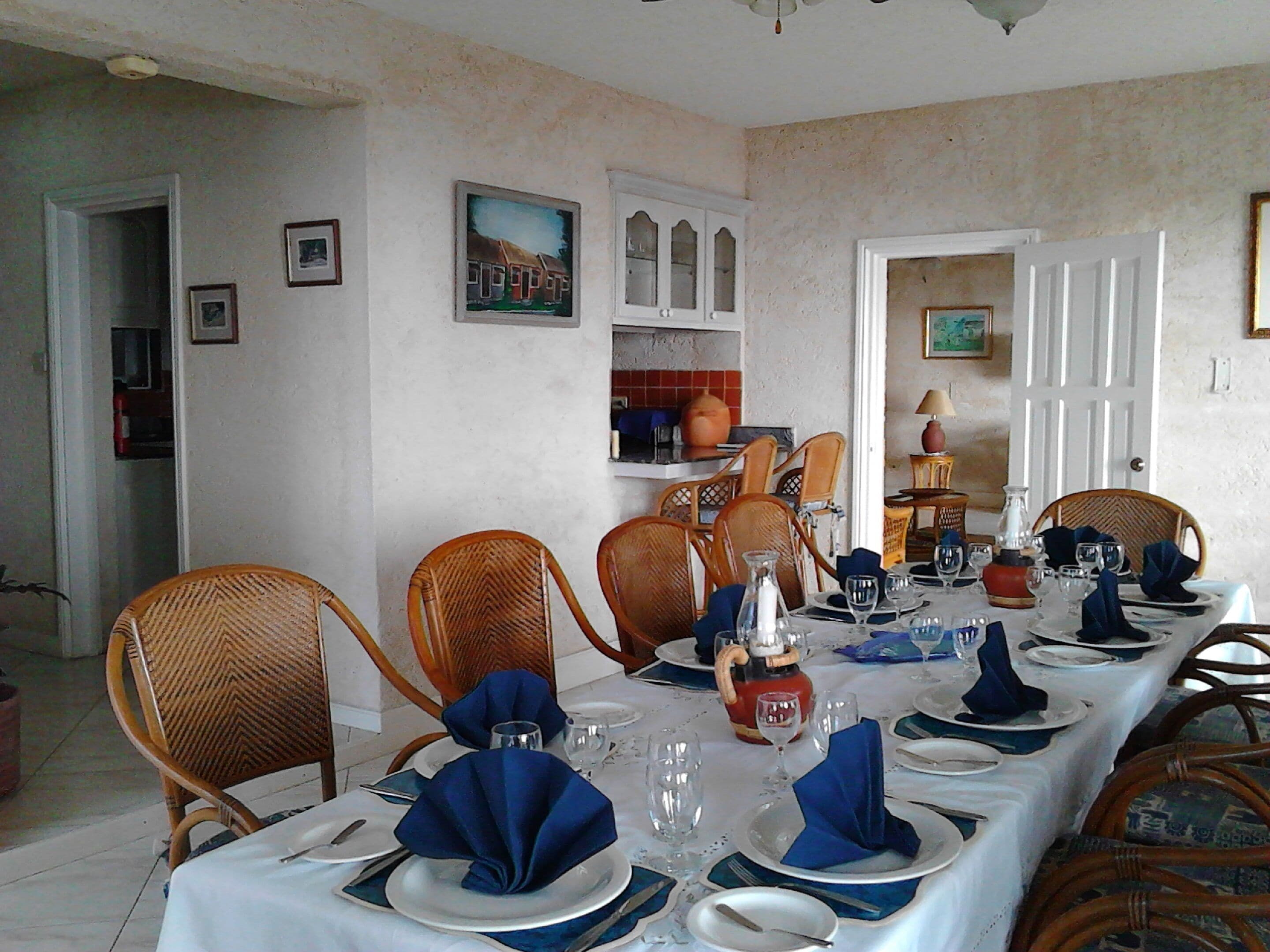Een eetkamer met een lange tafel gedekt voor een maaltijd, omringd door rieten stoelen.