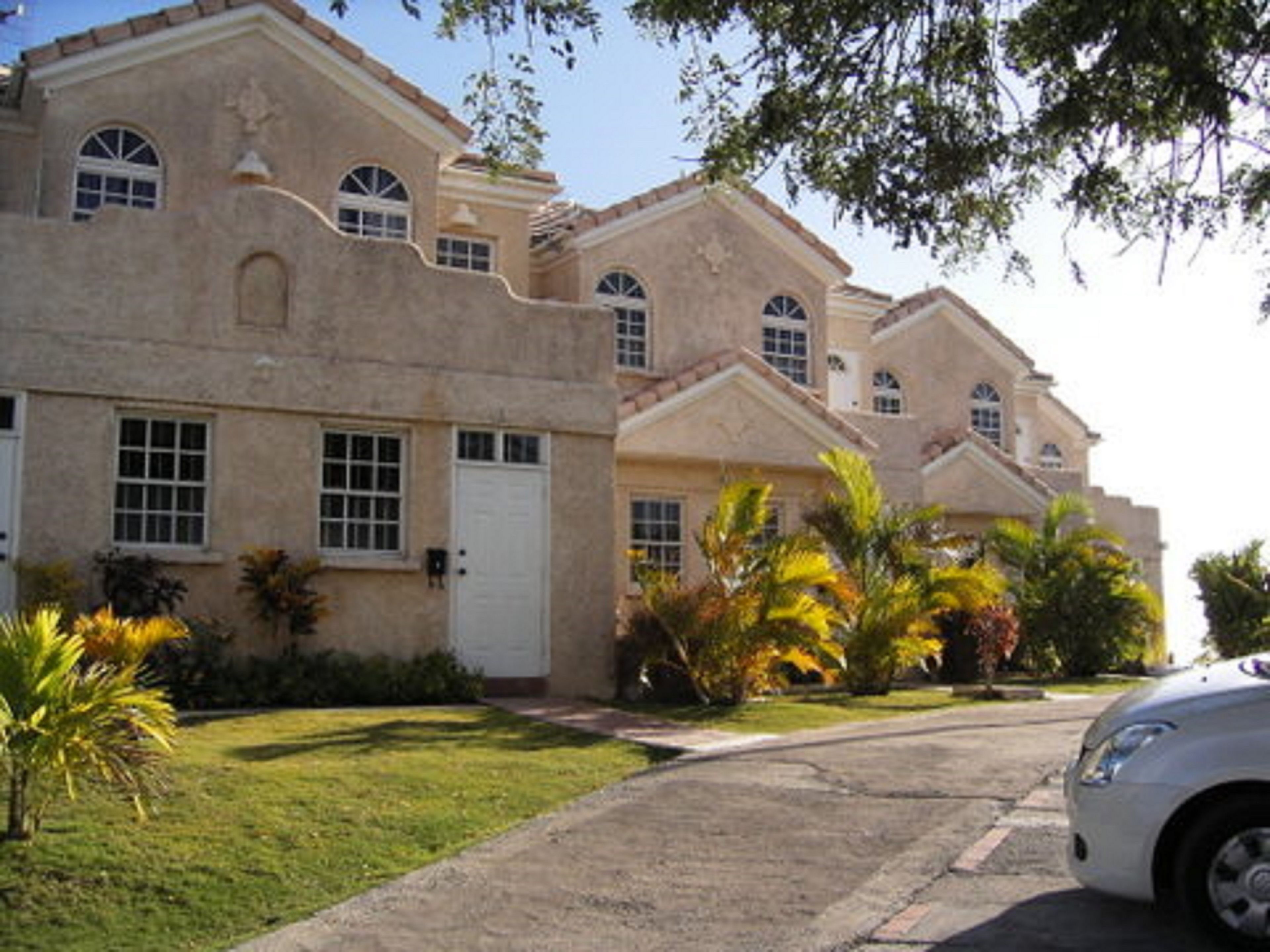 A large, multi-story building with a stucco exterior, multiple windows, and a paved driveway.