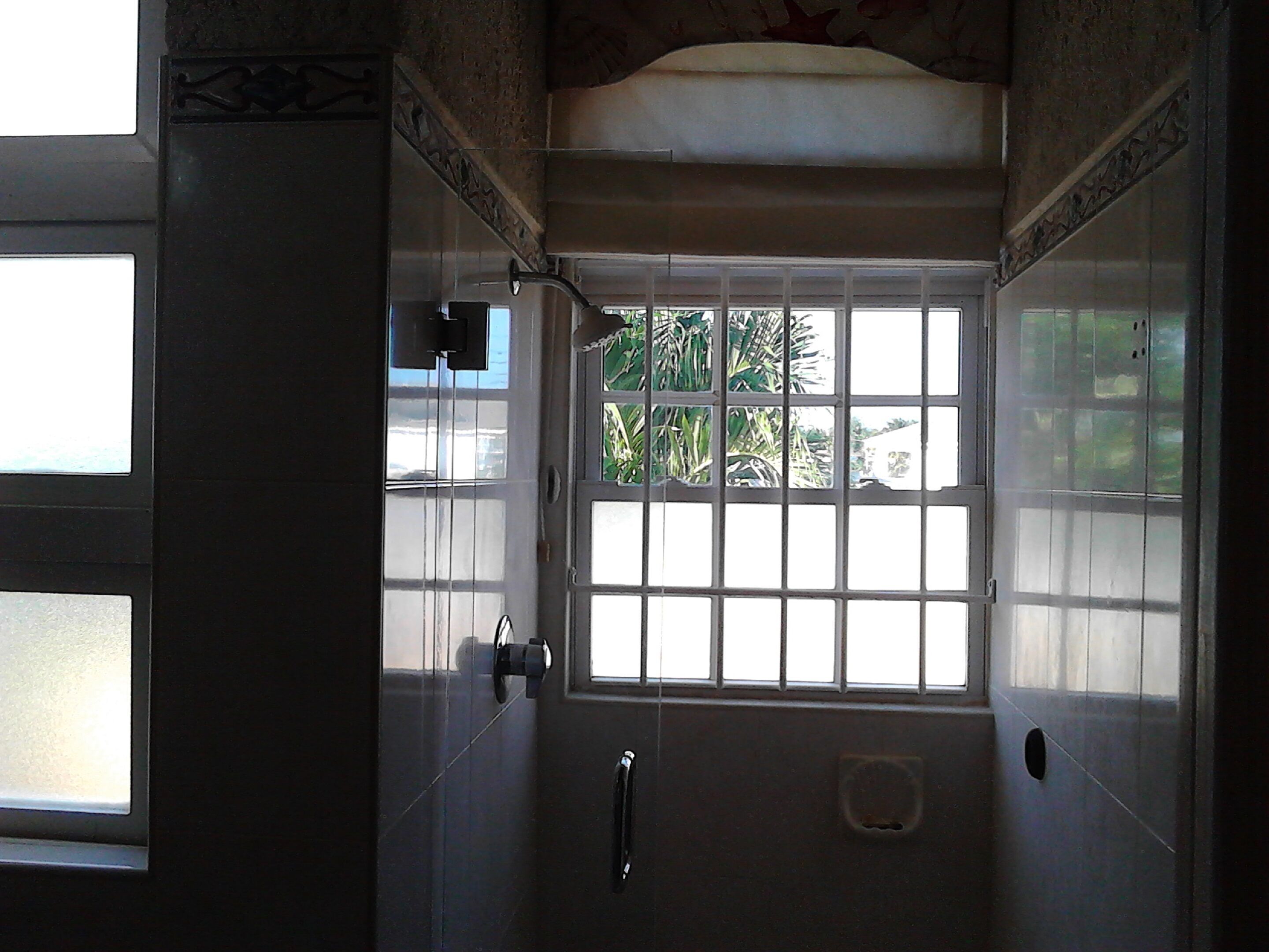 A bathroom with a window, a towel rack, and a shower area.