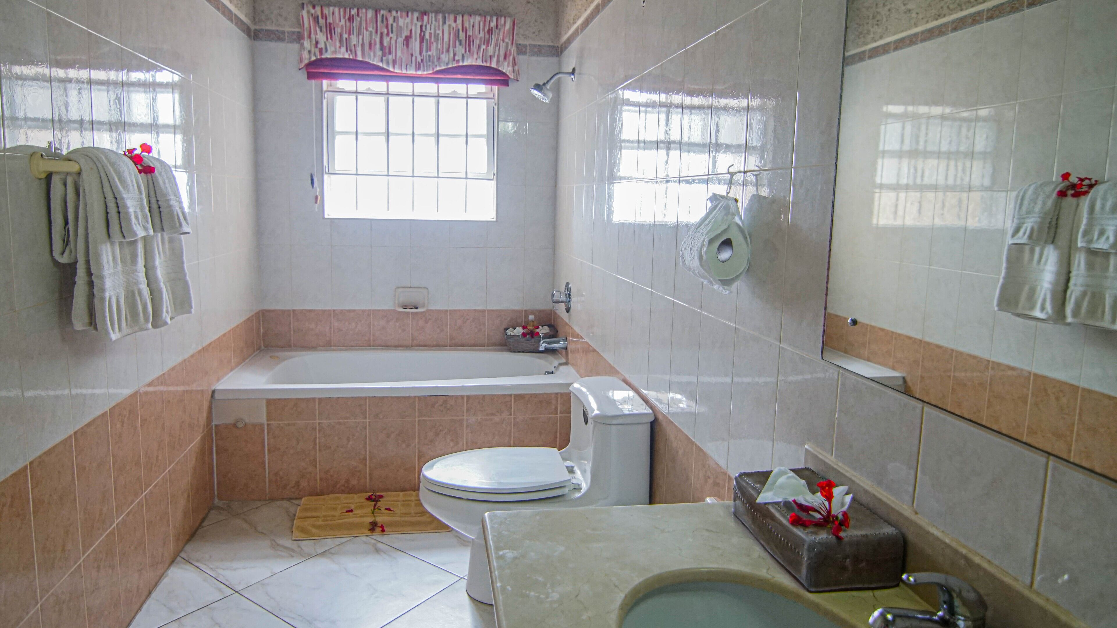 A bathroom with a bathtub, toilet, sink, and a window with a curtain.