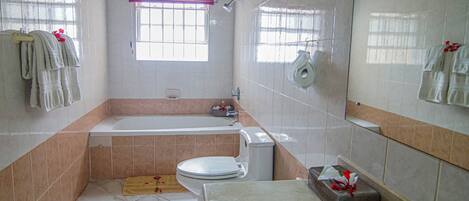 A bathroom with a bathtub, toilet, sink, and a window with a curtain.
