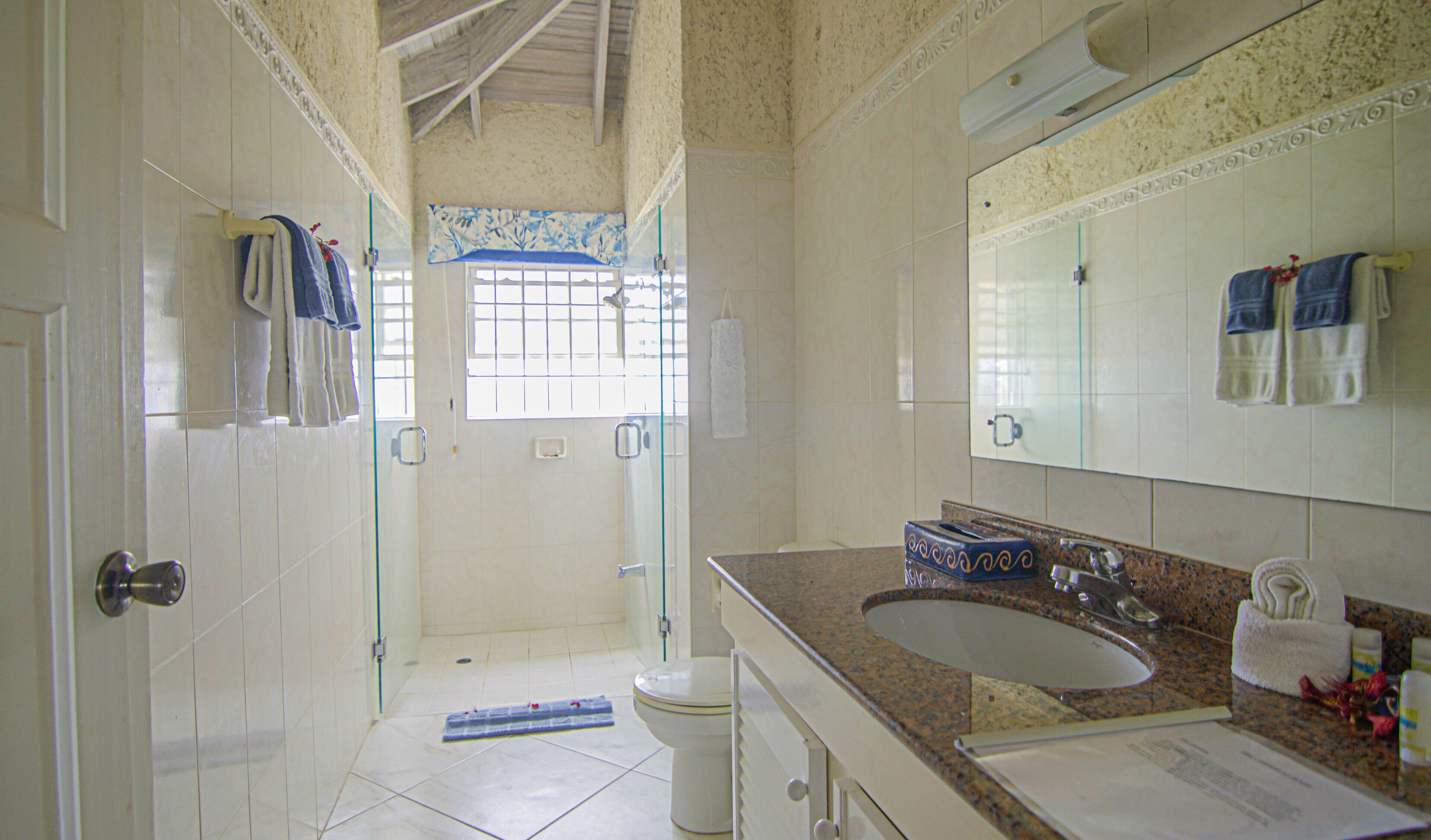 Un baño con ducha, inodoro, lavamanos y un espejo grande.