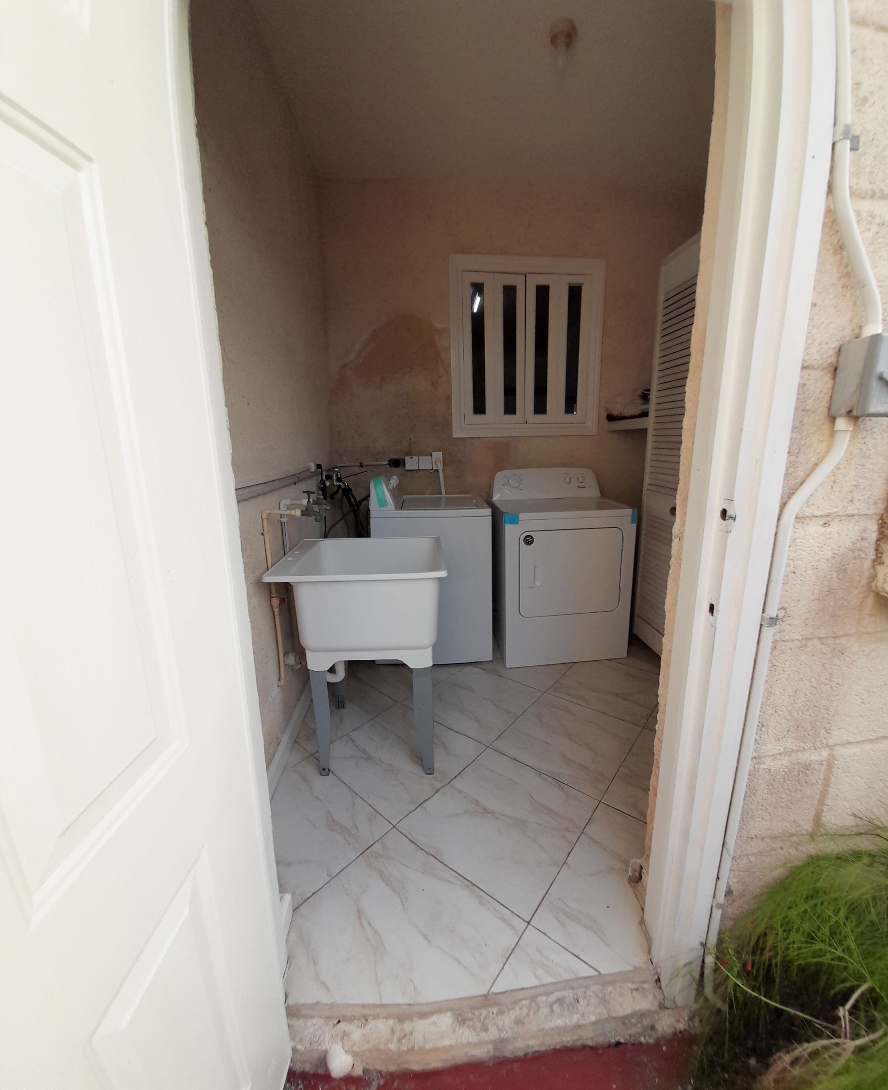 A small laundry room with a washing machine, dryer, and a sink.