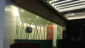 A reception area with a modern design, featuring a reception desk, a television screen, and a sign indicating the location of the elevator. - Hotel Amala (Mexico City)