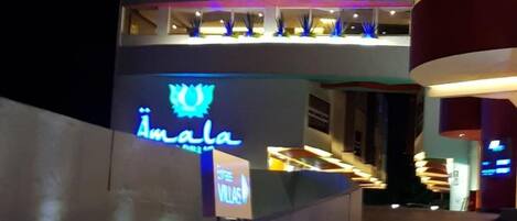 Ein Hotel mit einem auffälligen Neonlichtschild mit der Aufschrift "Amala" und einem Schild, das einen Coffeeshop kennzeichnet.