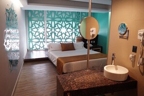 Habitación de hotel con cama, un espejo grande, un lavamanos y un adornado en la pared.