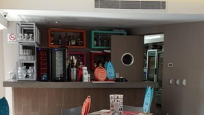 A modern dining area with tables and chairs, a bar area with shelves of bottles and glasses, and a no smoking sign on the wall. - Hotel Amala (Mexico City)