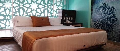 Una cama bien hecha con una colcha blanca y marrón, un cabecero de madera y un panel decorativo en la pared con un diseño geométrico.