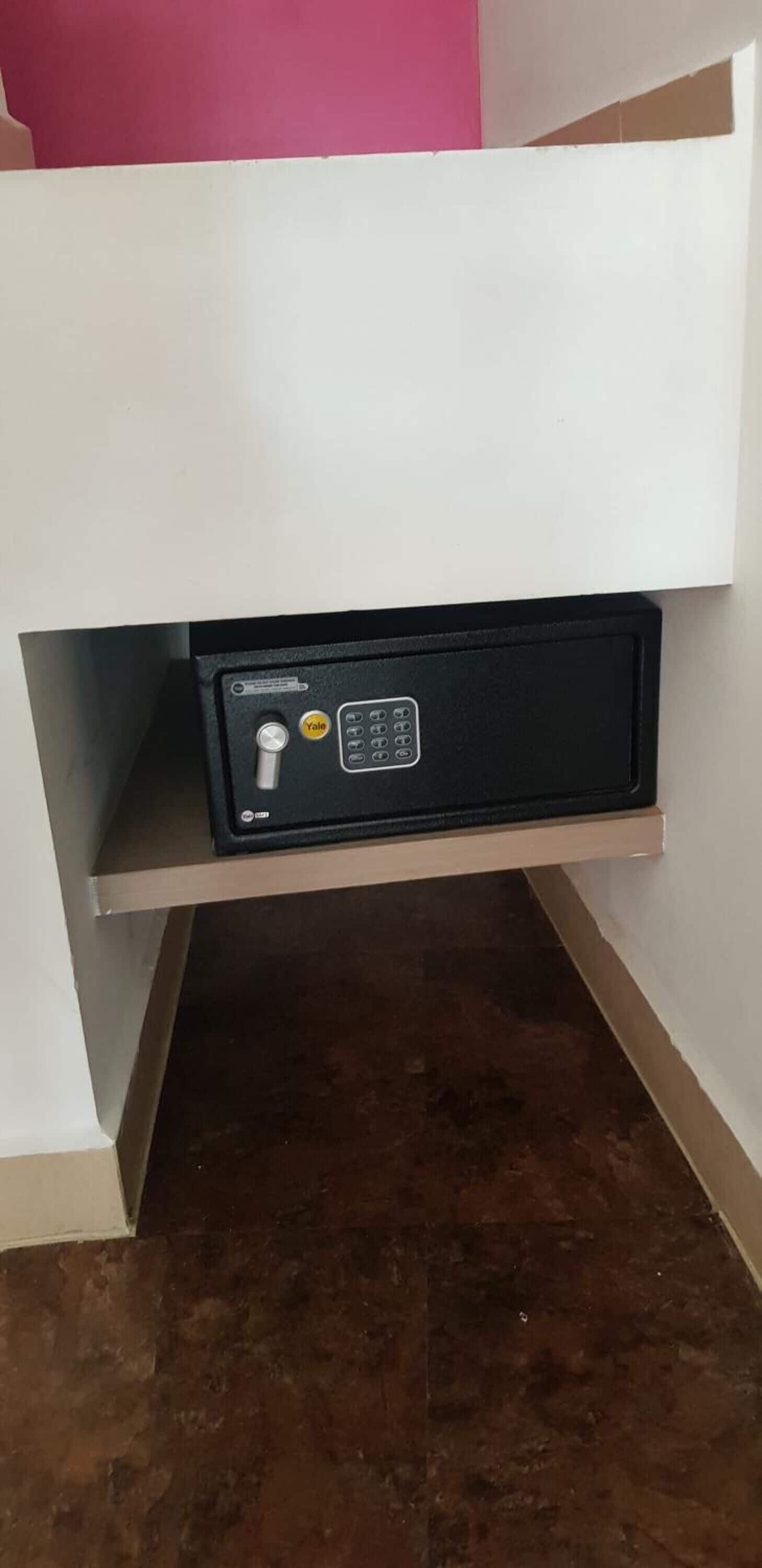 A white cabinet with a black safe on a shelf.