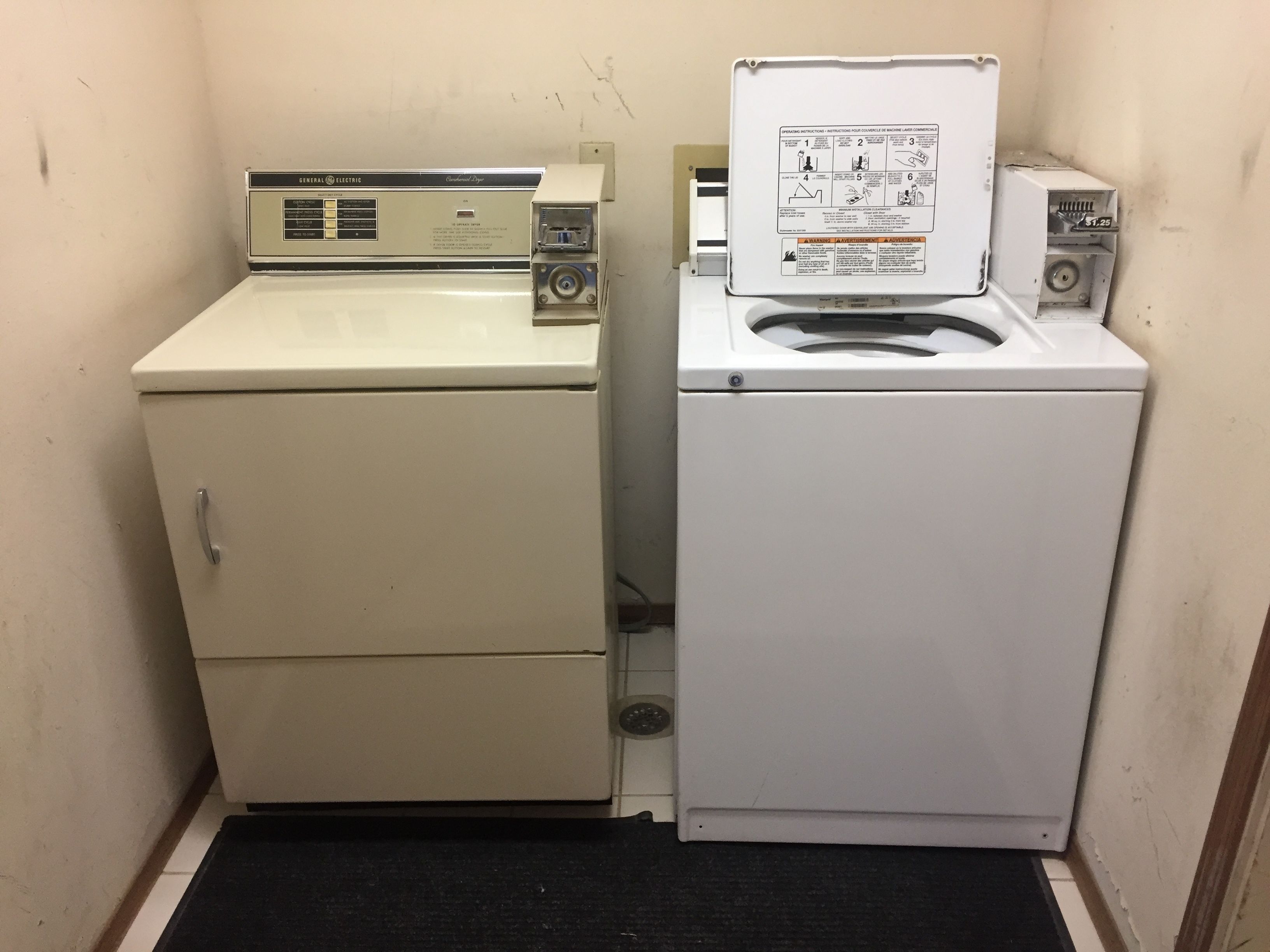 A compact laundry room with two washing machines, one with a front-loading door and the other with a top-loading door.