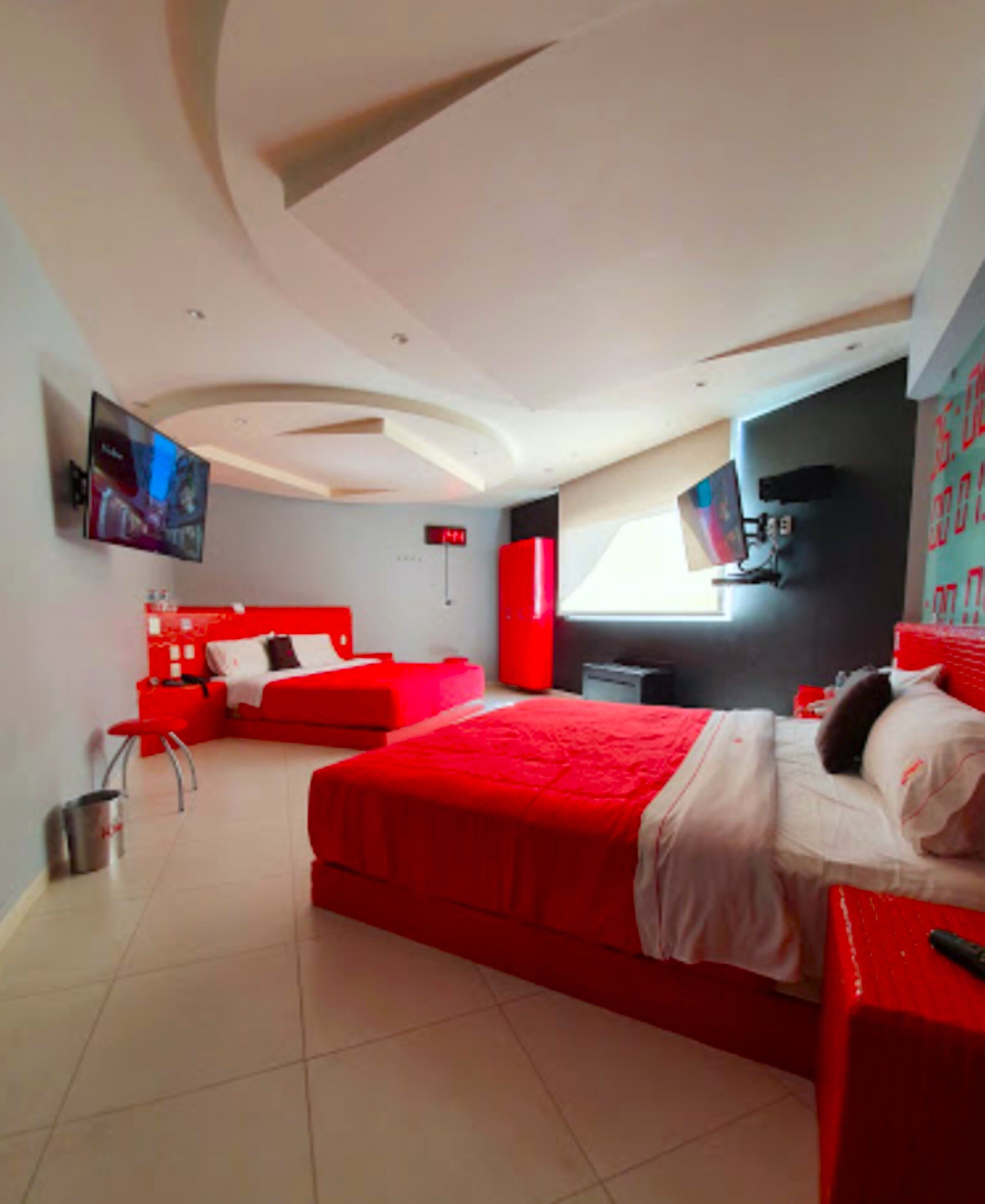 Un dormitorio moderno con una cama grande, un sofá rojo, un televisor y un armario rojo.