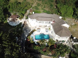Una casa grande con piscina, terraza cubierta y antena parabólica.