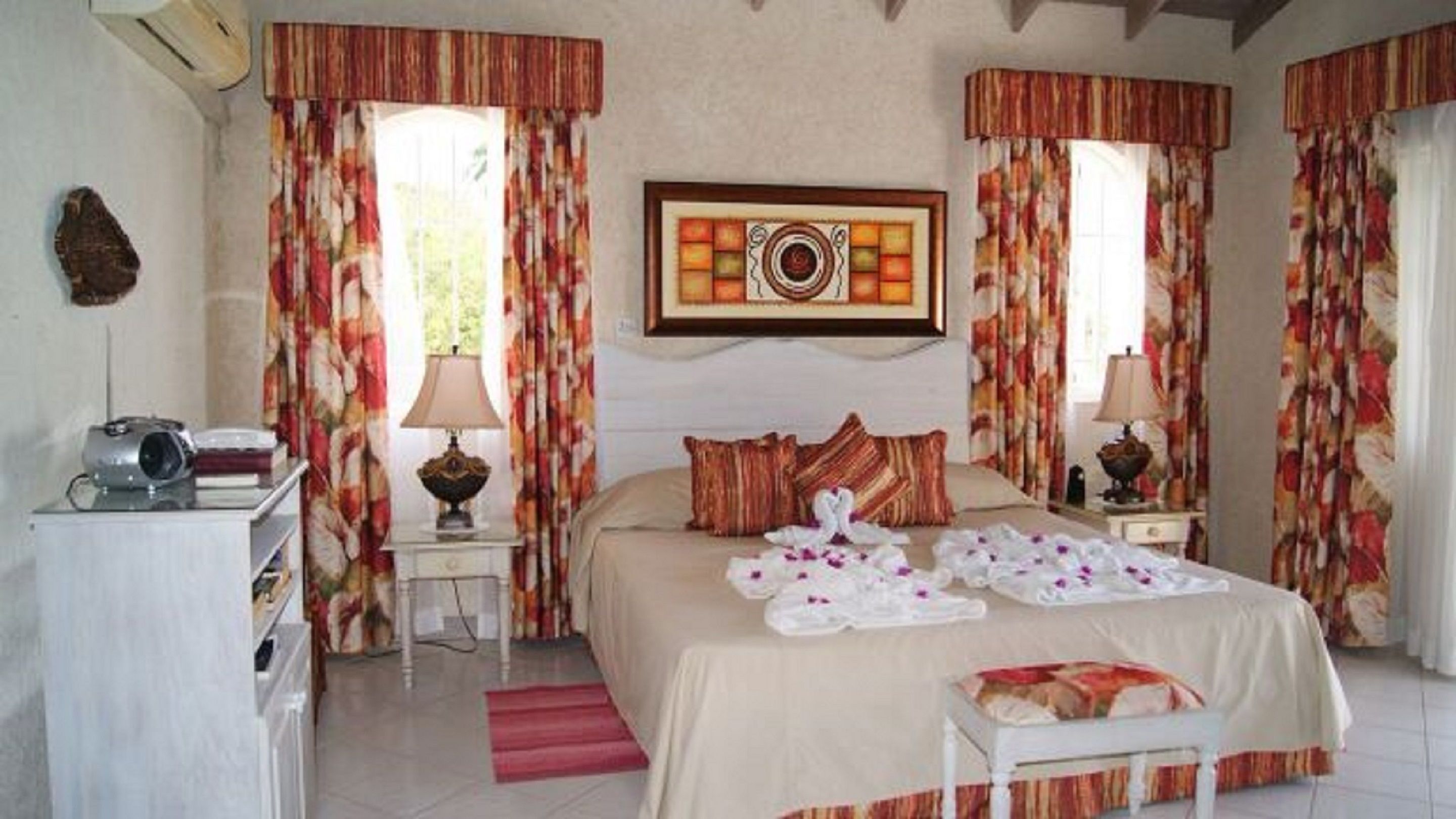 A hotel room with a bed, two bedside tables, a lamp, a framed picture, and curtains.