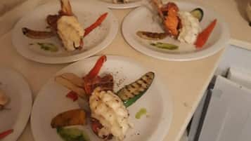 A kitchen counter with several plates of food, including grilled vegetables and seafood.