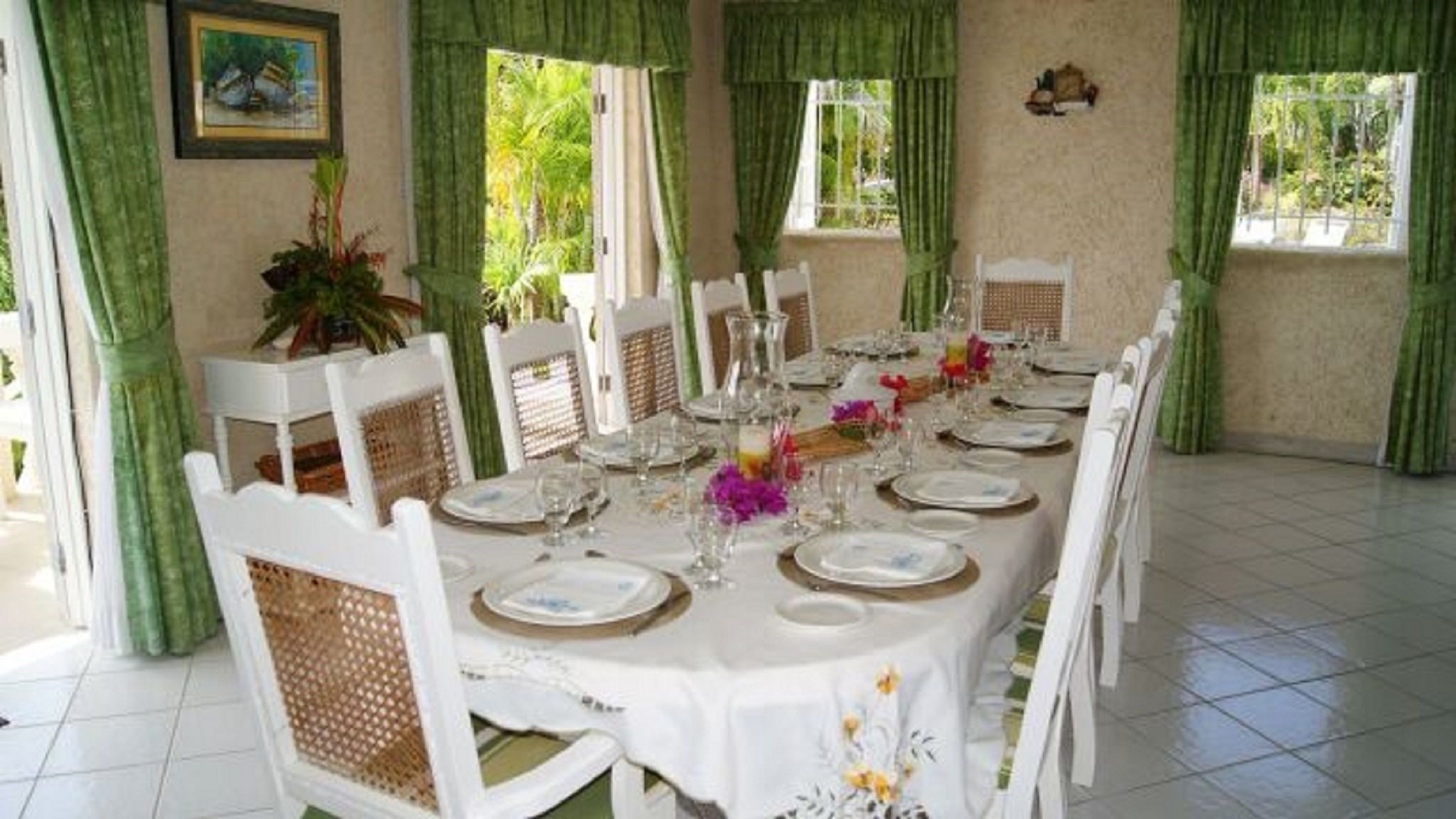 A dining area with a long table set for a meal, surrounded by chairs.