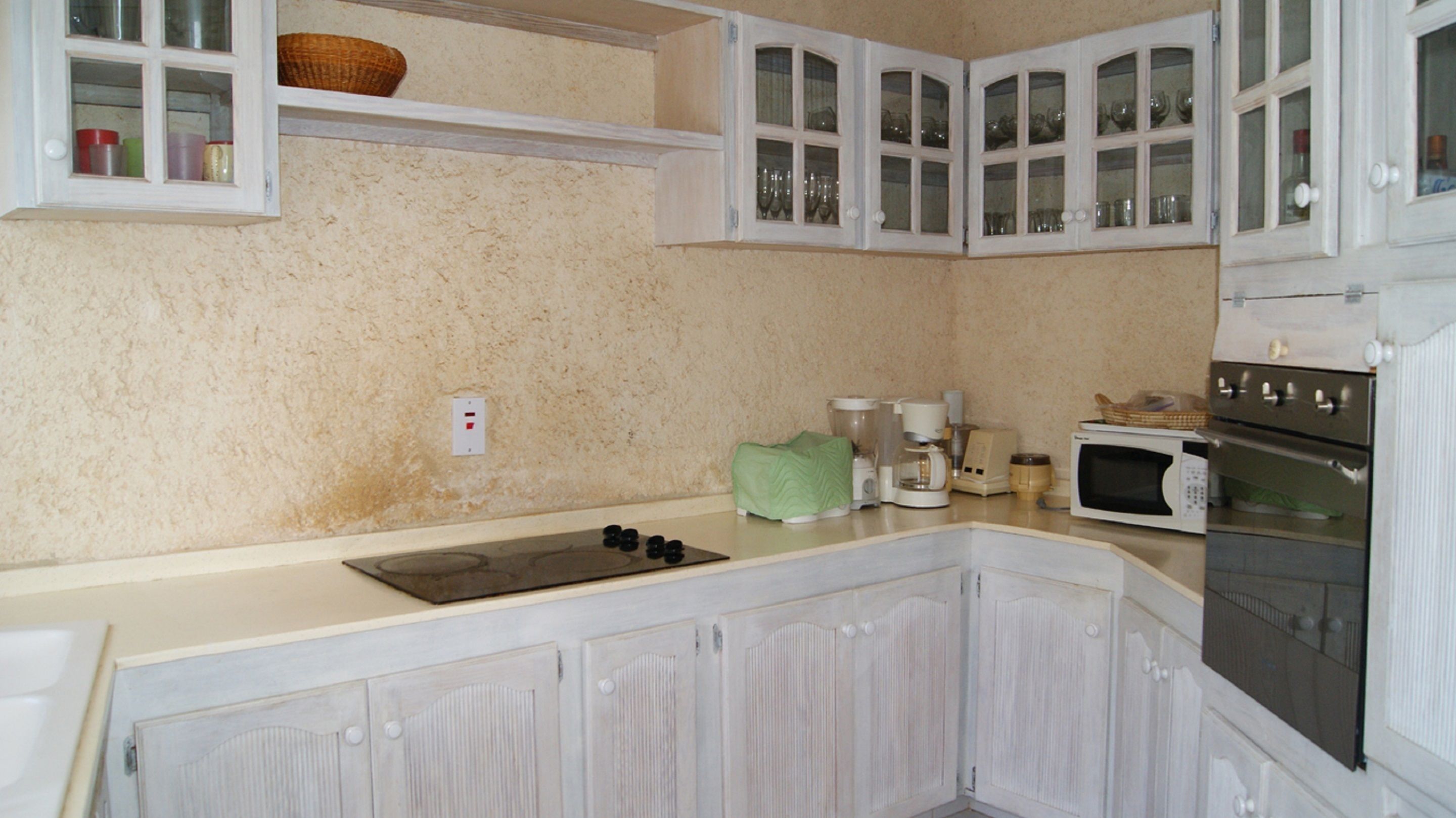 A kitchen with white cabinets, a microwave, a stove, and a coffee maker.