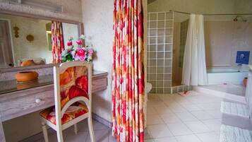 Um banheiro com toucador de madeira, espelho, área de chuveiro com porta de vidro e vaso sanitário.